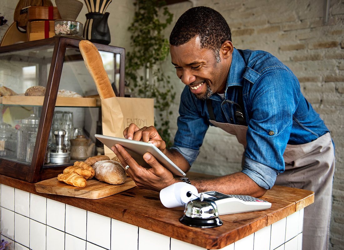 Business Insurance - Man Using Tablet for Online Business Orders at His Bakery Shop